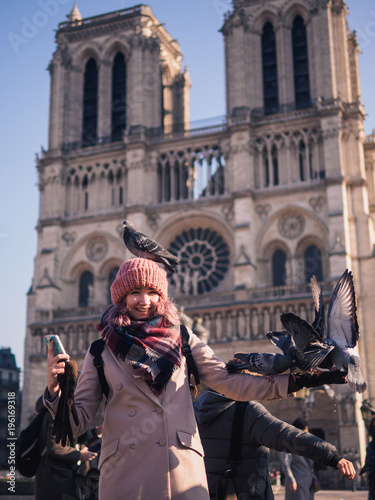 Girl feeding pigeons in the square in front of the cathedral of Notre Dame © paulzhuk