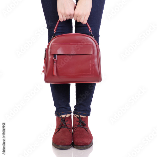 Female legs in jeans and in red suede shoes with red leather bag handbag