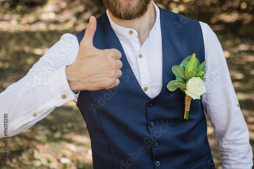 Handsome elegant bearded groom in checkered suit is standing on the bridge in the forest. Stylish wedding grooms photo. Rustic hipster portrait. photo