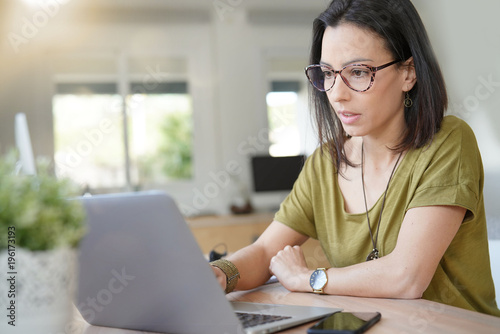 Woman with eyeglasses in office working on laptop
