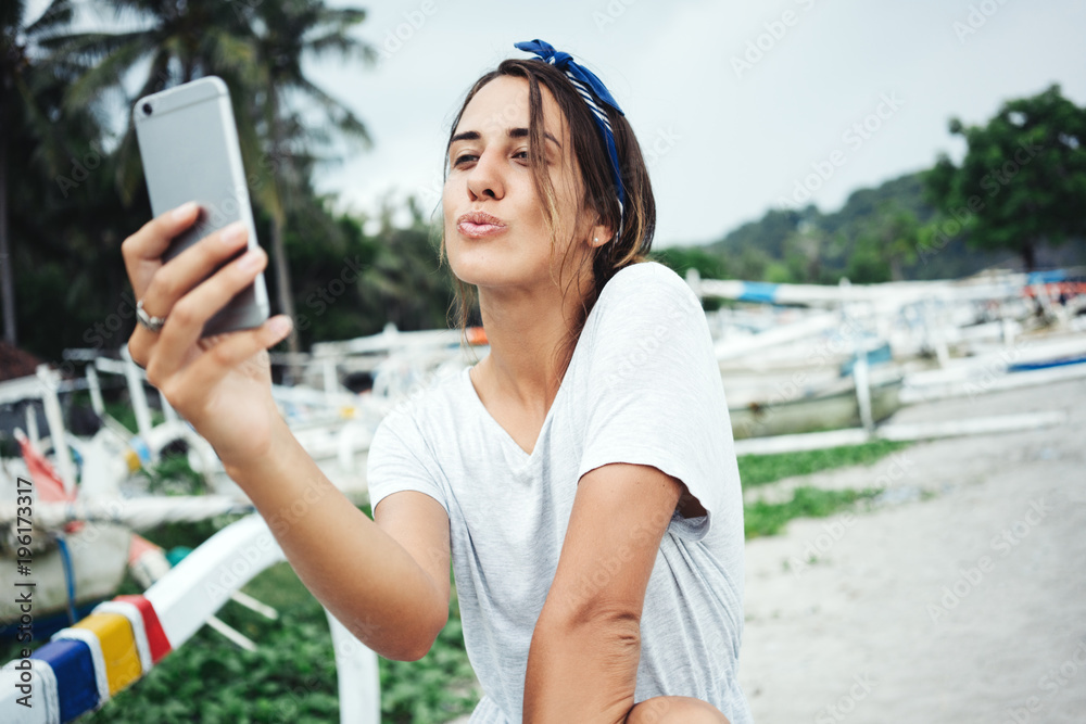 Beauty woman near the ocean, smiling and taking photo using mobile phone