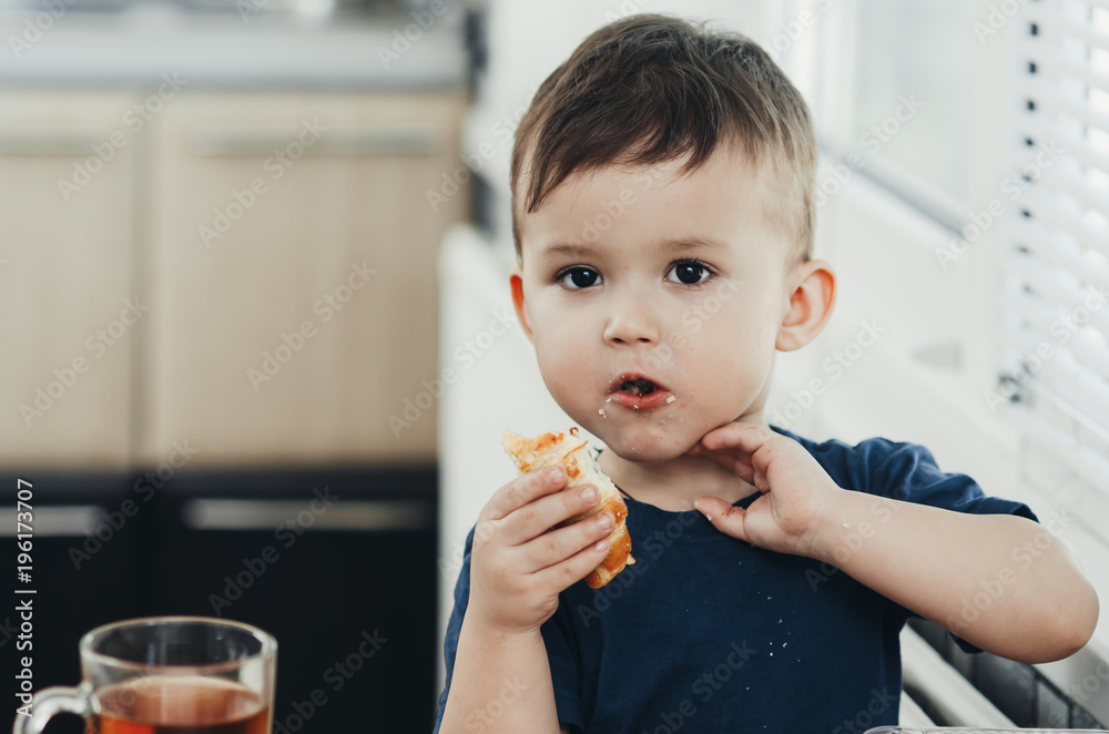 Beautiful baby sitting in the kitchen eating a delicious tube of condensed milk Beautiful baby sitting in the kitchen eating a delicious tube of condensed milk