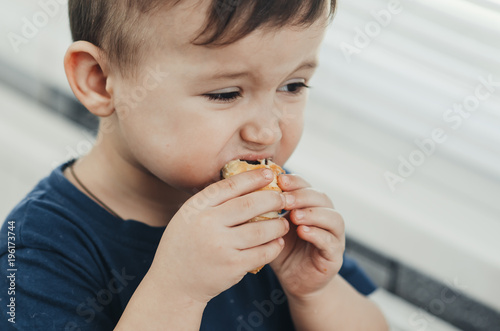 Beautiful baby sitting in the kitchen eating a delicious tube of condensed milk