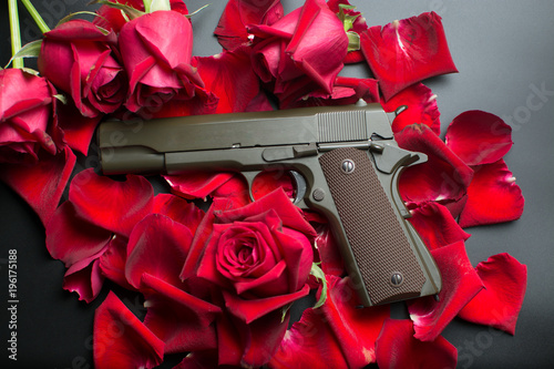Gun and red roses flower on dark background