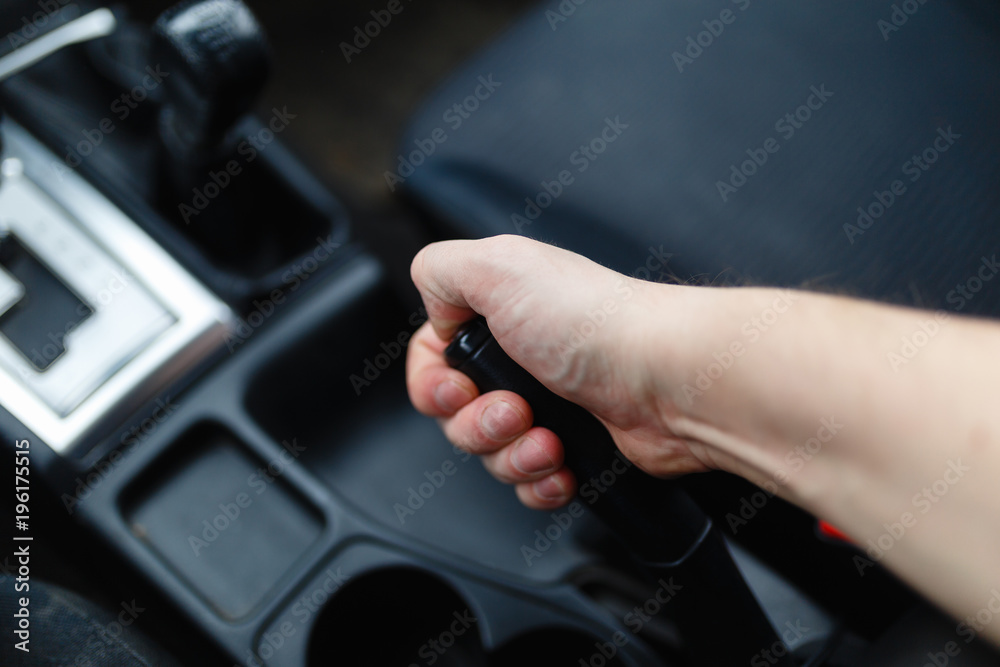 The driver pulls the hand brake lever. Male hand pulling the Parking brake using the hand brake lever. Hand brake for emergency stopping. The driver pulls the hand brake lever. Male hand pulling the Parking brake using the hand brake lever. Hand brake for emergency stopping.