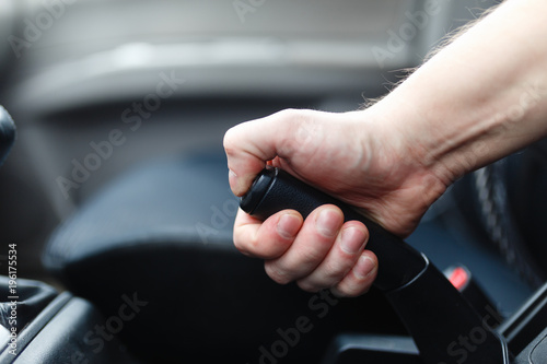 The driver pulls the hand brake lever. Male hand pulling the Parking brake using the hand brake lever. Hand brake for emergency stopping.