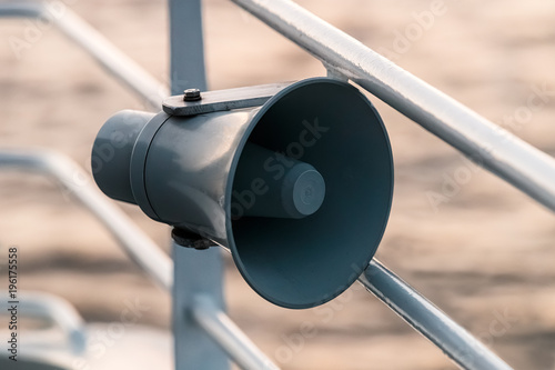 Loudspeaker on the ship's guardrail against background of sea surface.