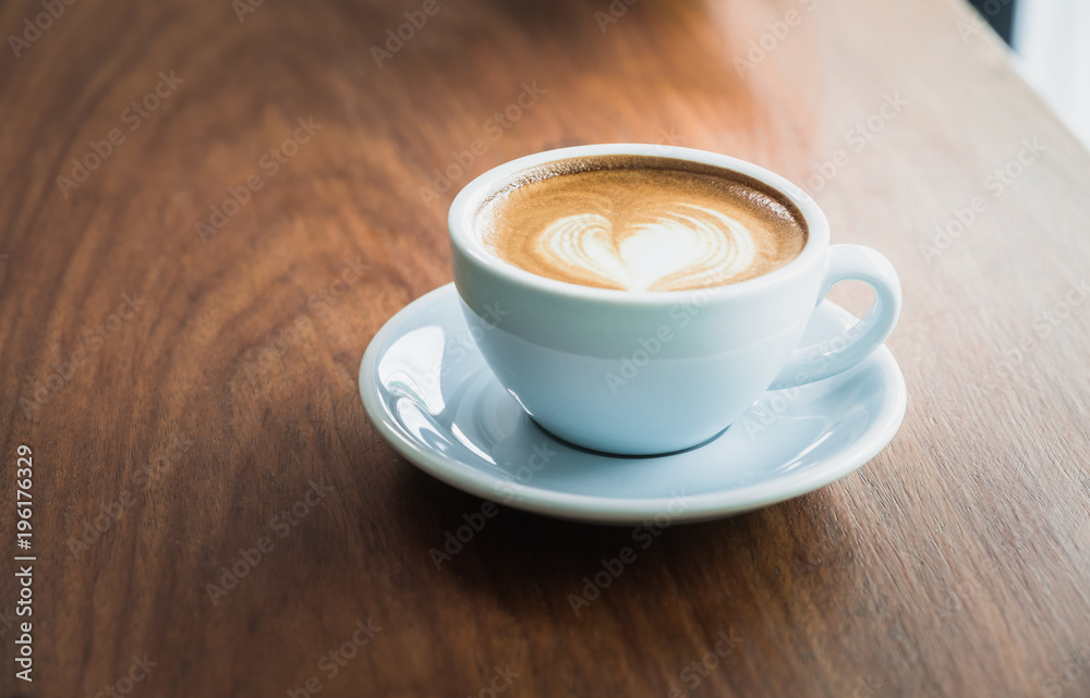 Close up hot cappuccino coffee cup with heart shape latte art on wood table at cafe,Drak tone filter,food and drink .