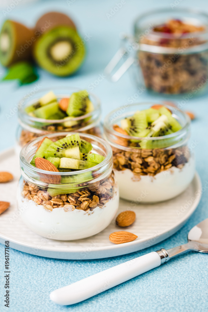 Kiwi granola parfait with nuts and greek yogurt in glass jars. Selective focus, space for text. Kiwi granola parfait with nuts and greek yogurt in glass jars. Selective focus, space for text.