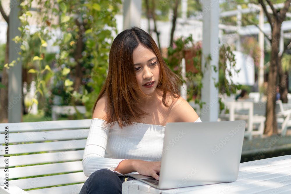 Beautiful young woman watching something on laptop in the garden. Beautiful young woman watching something on laptop in the garden.