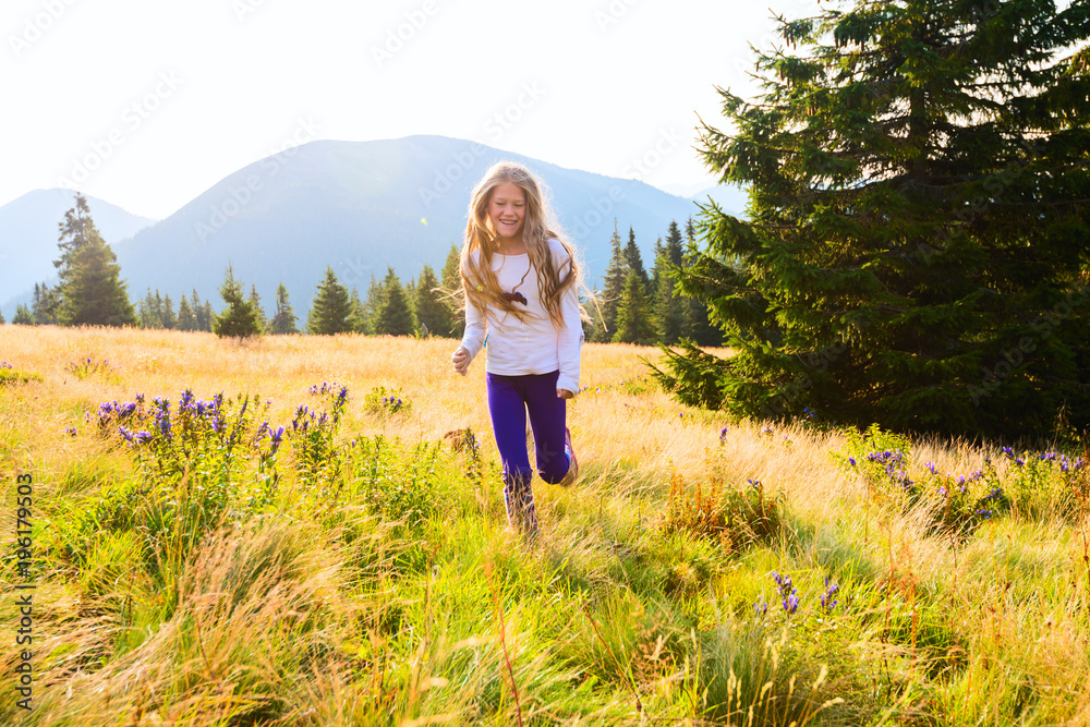 Happy teenage girl runs along the alpine meadow Happy teenage girl runs along the alpine meadow
