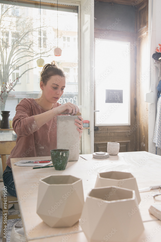 A ceremic artist is putting the finishing touches to a ceramic pitcher in a pottery workshop. A ceremic artist is putting the finishing touches to a ceramic pitcher in a pottery workshop.