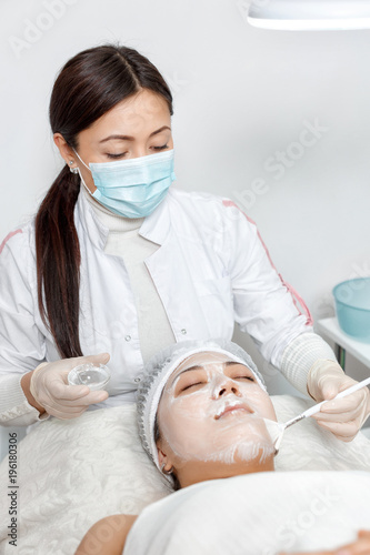 cosmetologist puts a mask on the face