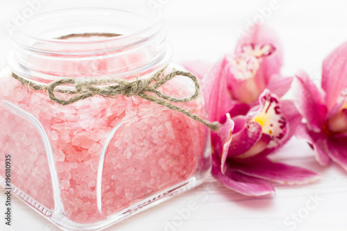 Spa and wellness setting with orchid and rose sea salt in a can on wooden white background closeup