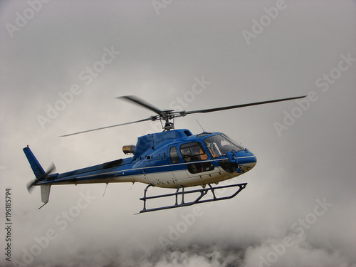 Fototapeta Naklejka Na Ścianę i Meble -  Blue helicopter flying in clouds