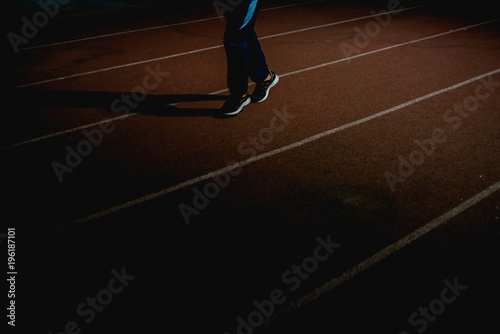 Athletics people running on red running track at night