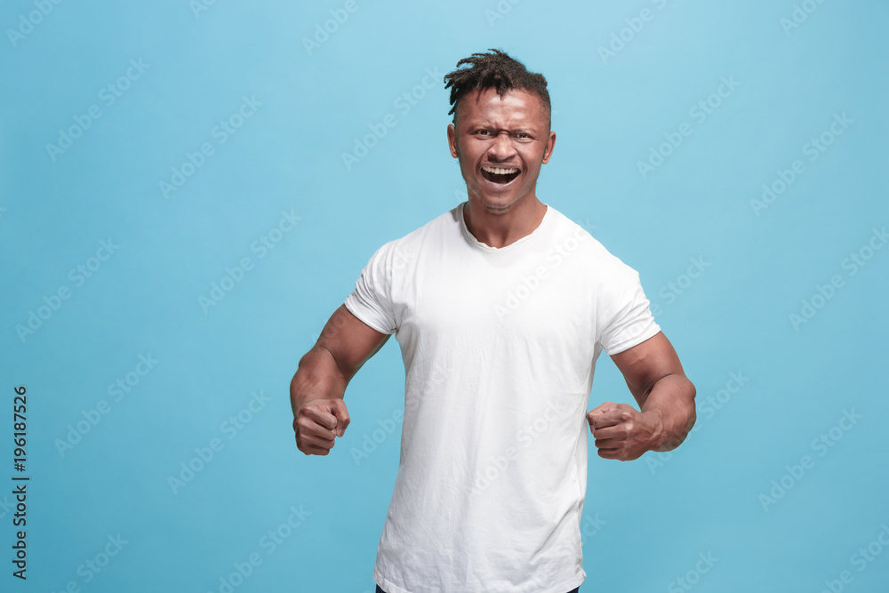 The young emotional angry afro man screaming on blue studio background The young emotional angry afro man screaming on blue studio background