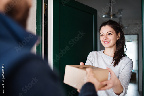 Woman receiving parcel from delivery man at the door. photo