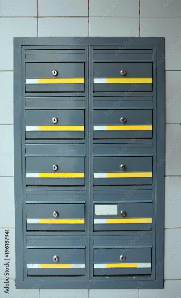 grey steel modern lockable mailboxes in a tiled exterior wall with yellow and white labels grey steel modern lockable mailboxes in a tiled exterior wall with yellow and white labels