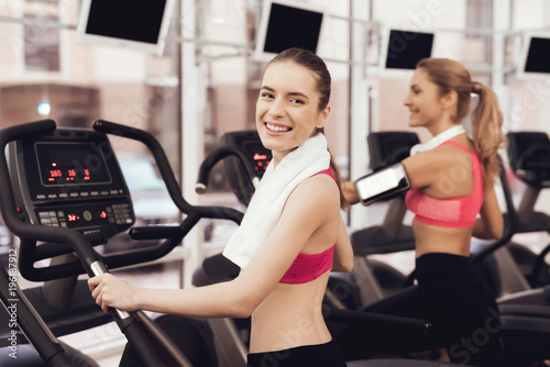Woman and girl running on treadmill at the gym. They look happy, fashionable and fit.