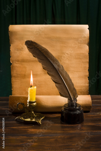 The concept of education and writing, an inkwell with a pen and a candle on the background of a roll of parchment
