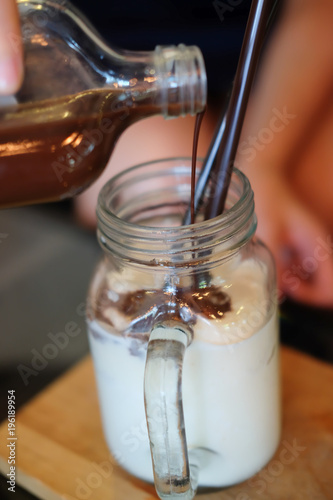 Pours coffee into glass of milk