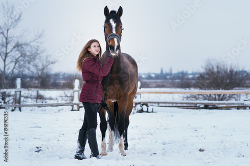 young woman with a horse on nature in winter on snow