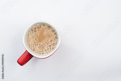 top view of foamy milk coffee or milk tea in a red mug isolated on white background