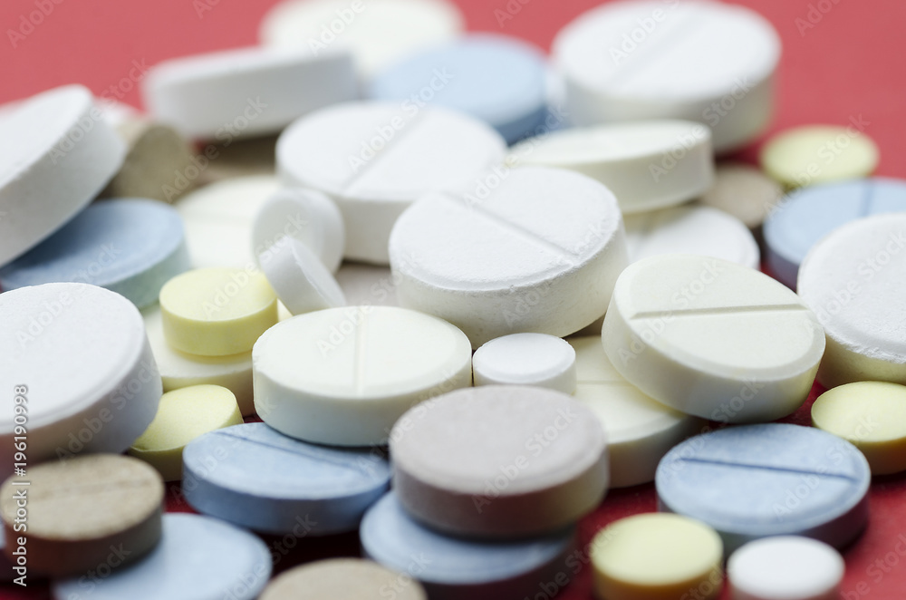 Round colored pill close-up on red background, soft focus