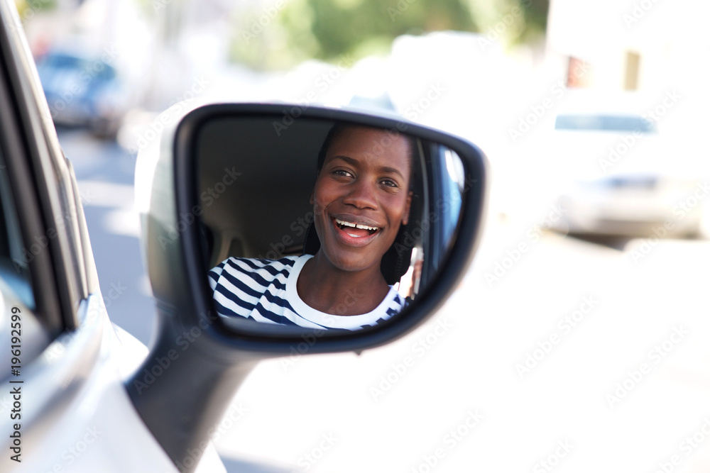 Close up happy african woman driving car and looking in side mirror