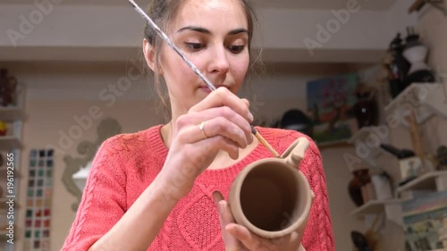 Female ceramist correct the surface on the aw clay cup using the tassel. photo