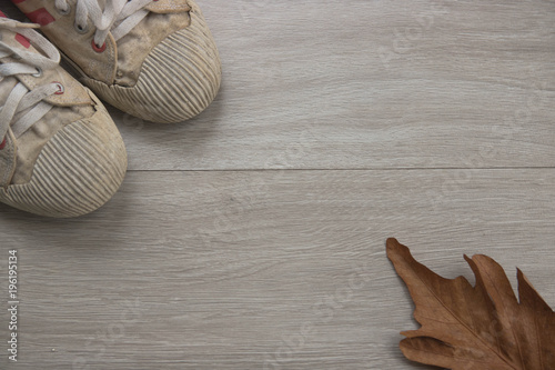 Old white sneakers lay on wooden floor looking from the top view. photo