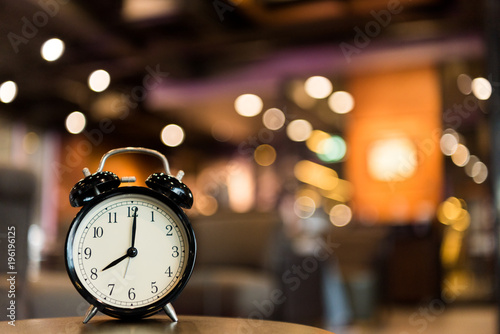 black vintage alarm clock with blurred colorful light background.