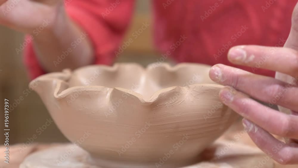 Closeup view of a ceramist smoothing the clay pot edges using the tassel. Closeup view of a ceramist smoothing the clay pot edges using the tassel.