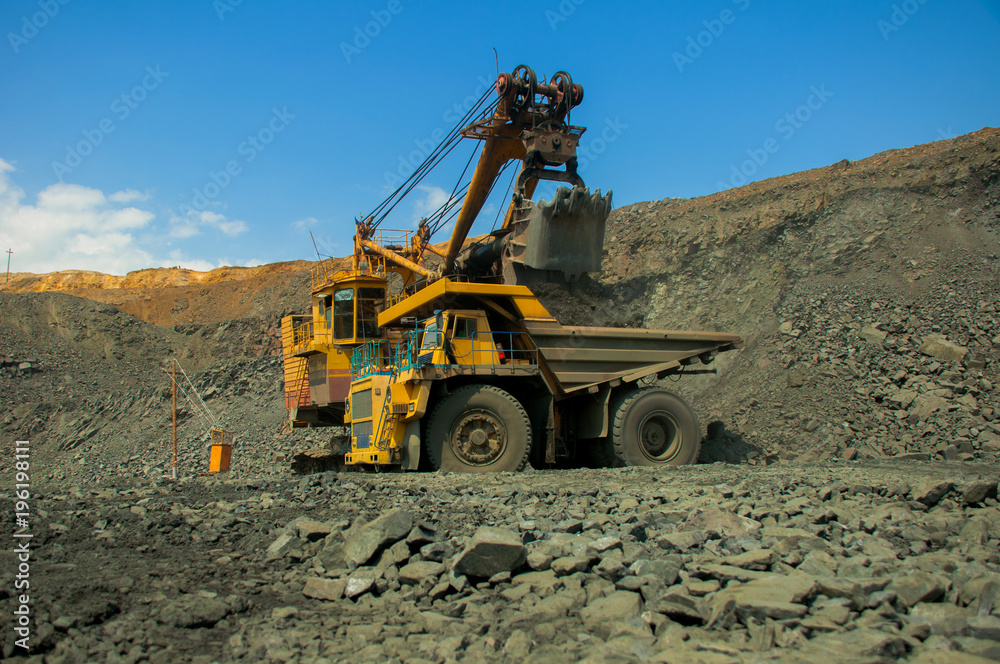 Excavator in the quarry loads the dumper with iron ore