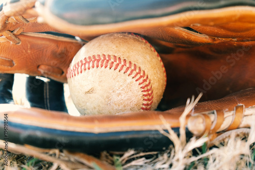 Baseball ball in leather glove.  Used equipment for the sport.