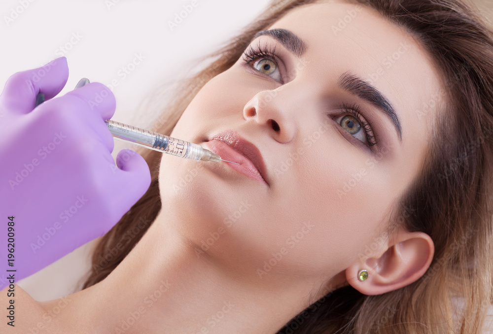 woman receiving a botox injection in her lips, close up.