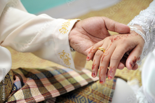 malay wedding groom bolstering silver ring on bride's finger
