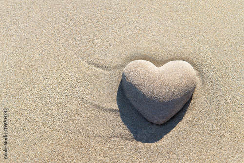 Heart made of sand with shadow on sandy beach background, Saint Valentines day greeting cards, romantic, love or proposal concept.