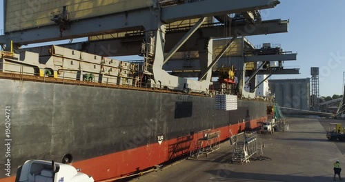 Drone tracking toward ship loading aluminium ingots at sunset for export from Australia - 4K 30P. 