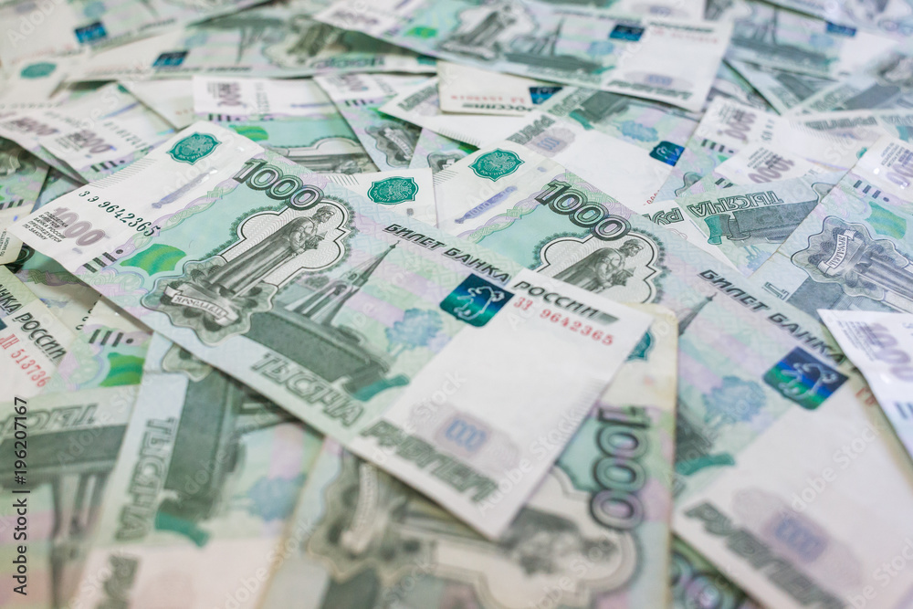A lot of banknotes in nominal value of one thousand Russian rubles lie in a disorderly heap on the table. A lot of banknotes in nominal value of one thousand Russian rubles lie in a disorderly heap on the table.