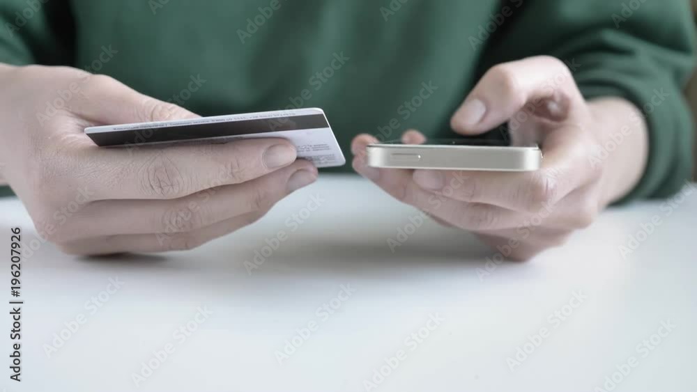 Female hands hold a white smartphone and a credit card, online banking, shopping 60 fps Female hands hold a white smartphone and a credit card, online banking, shopping 60 fps