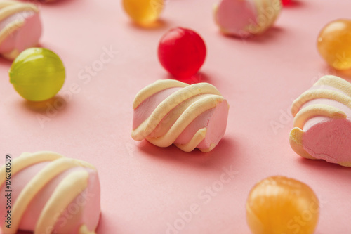 Closeup of marshmallows and colourful sweets on pink background