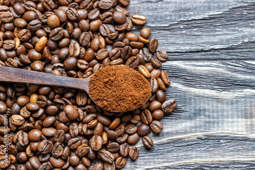 A coffee cup with coffee beans on an old wooden table. Fried coffee beans on a wooden background. Viewing from above.