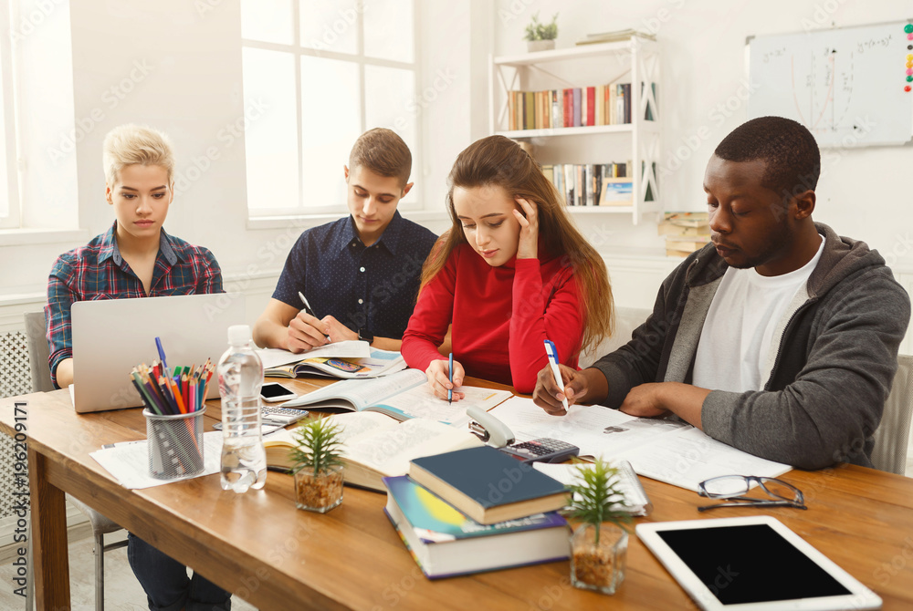 Group of diverse students studying at wooden table Group of diverse students studying at wooden table