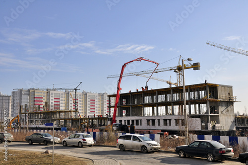 close-up construction of a multi-storey house of blocks and bricks. Construction equipment and workers carry out installation of the building and conduct preparatory work. © ESENIY