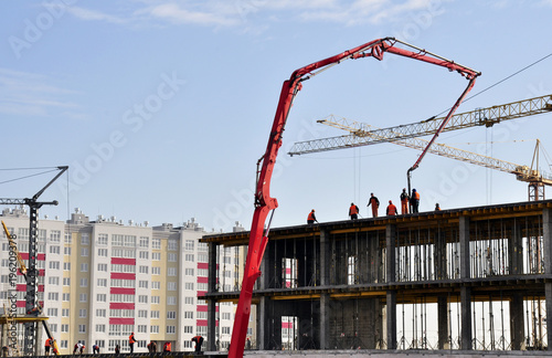 close-up construction of a multi-storey house of blocks and bricks. Construction equipment and workers carry out installation of the building and conduct preparatory work.