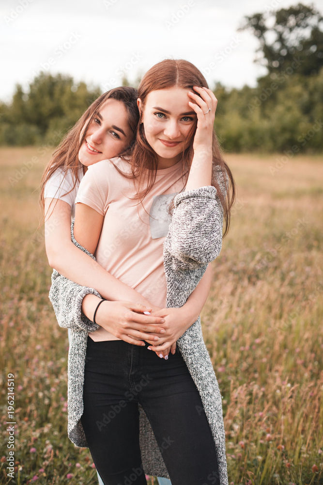 Two young women are hugging on the field at evening Two young women are hugging on the field at evening