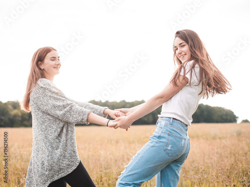 Two young women are dancing on the field at evening