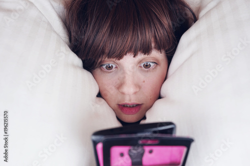 Mujer joven con insomnio enganchada a su teléfono móvil  photo